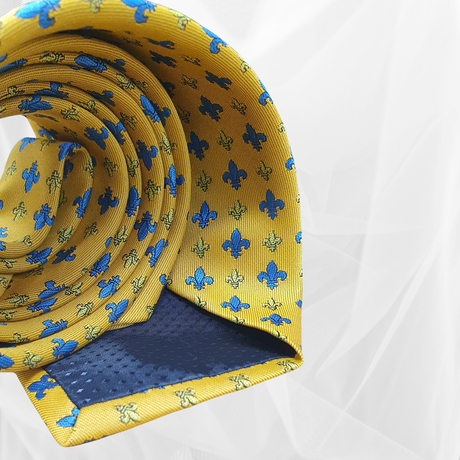 Yellow tie with blue and gold fleur-de-lis pattern, rolled on white background